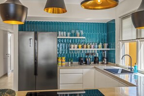 A modern kitchen with a stainless steel refrigerator, white cabinets, a blue backsplash, and a window with blinds. - The Strand apartment 1A, 5 guests with pool and beach (Willemstad)