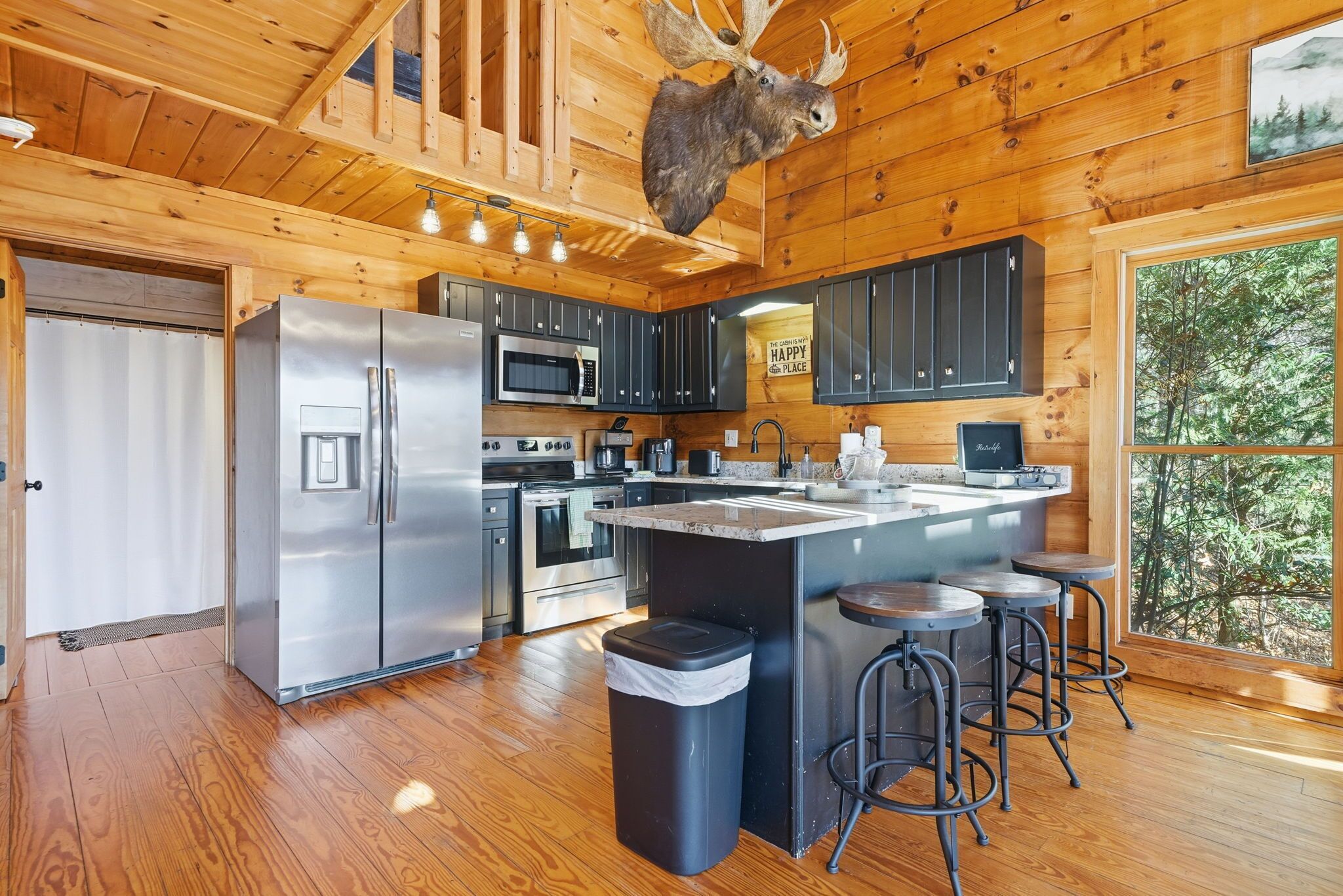 Eine moderne Küche mit Holzwänden, Edelstahlgeräten und einer großen Kochinsel mit Sitzgelegenheiten.