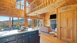 A wooden cabin interior with a large kitchen island, dining area, and a fireplace. - Best views in Cherry Log, Putting Green, Hot Tub (Cherry Log)