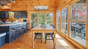 A wooden cabin interior with a kitchen, dining area, and large windows. - Best views in Cherry Log, Putting Green, Hot Tub (Cherry Log)