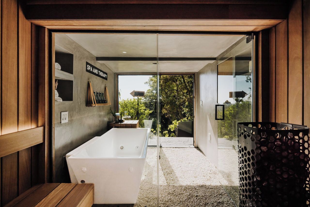 A modern bathroom with a large bathtub, a wooden bench, and a sign indicating a spa and therapy area.