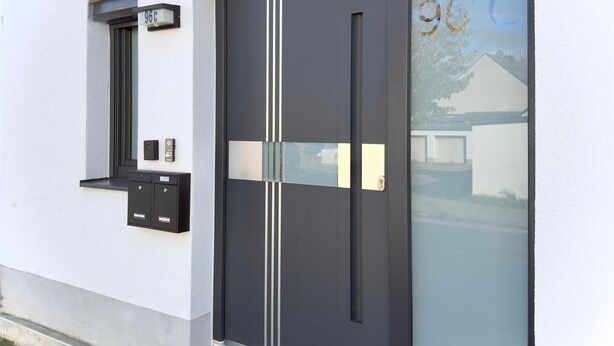 Un edificio moderno con una puerta negra, un buzón y una ventana.