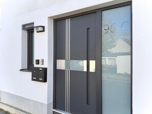 A modern building with a black door, a mailbox, and a window. - Apartment in the Grafschaft with Shared Terrace, Private Garden, and Wi-Fi (Gelsdorf)