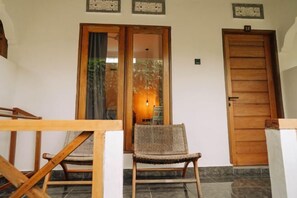 Une porte en bois, une chaise en osier et une porte vitrée avec un rideau.