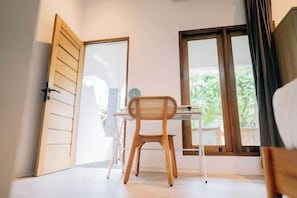 Une pièce avec un bureau en bois, une chaise et une fenêtre donnant sur un paysage verdoyant.