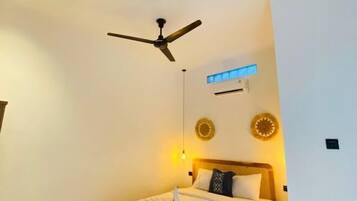 Una habitación de hotel con una cama, ventilador de techo, aire acondicionado instalado en la pared y decoración en las paredes.