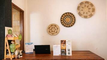 Un mostrador de recepción con una computadora portátil, folletos informativos y platos decorativos en la pared.