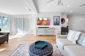 Una sala de estar moderna con un sofá, una mesa de centro y un televisor montado en la pared.