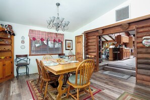A dining area with a wooden table, chairs, and a chandelier. - The Ohana Lodge - Rustic Log Cabin in Pinetop Country Club w/Deck, BBQ & B-Ball (Pinetop Country Club)