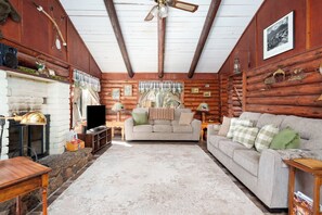 Ein rustikales Blockhaus-Interieur mit Kamin, Fernseher, Sofa und Dekoration.