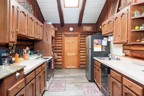 A kitchen with wooden cabinets, a refrigerator, and a clock on the wall.