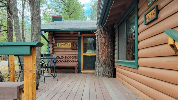 A wooden lodge with a porch, a bench, and a table. - The Ohana Lodge - Rustic Log Cabin in Pinetop Country Club w/Deck, BBQ & B-Ball (Pinetop Country Club)