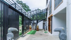 Un sendero estrecho que conduce a una escalera con barandilla de metal, flanqueado por estatuas y una cerca negra.