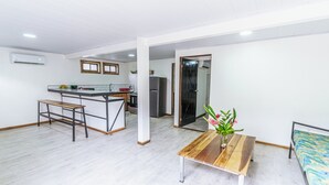 Una cocina moderna con una isla central, una mesa de comedor con un jarrón de flores y una cama con una colcha colorida.