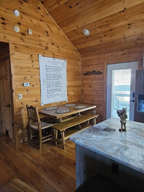 L’intérieur d’un chalet en bois comprend une table à manger, des bancs, un comptoir en marbre et un panneau fixé au mur.