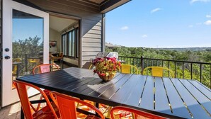 Un patio al aire libre con una mesa, sillas, una planta en maceta y vistas al paisaje.