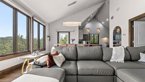 Una sala de estar moderna con un sofá modular, un comedor y una cocina al fondo.