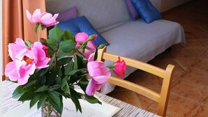 A room with a bed, a table with a vase of flowers, and a window with curtains. - Apartments Juras - Studio Apartment with Sea View (Mia) (Rogoznica)