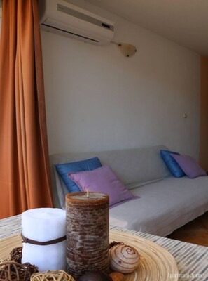 A room with a bed, a table with candles, and an air conditioning unit. - Apartments Juras - Studio Apartment with Sea View (Marija) (Rogoznica)