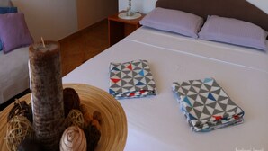Hotellihuone, jossa on sänky, tyynyjä, yöpöytä lampun kanssa ja koriste-esine sängyllä.