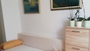 Um quarto pequeno e bem arrumado com um sofá, um armário e duas pinturas emolduradas na parede.