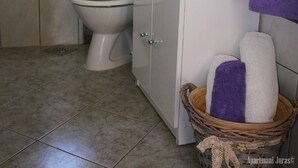 A bathroom with a toilet, sink, and shower. There is a window above the toilet, a towel rack, and a basket with towels. - Apartments Juras - Studio Apartment with Loggia (Ana) (Rogoznica)