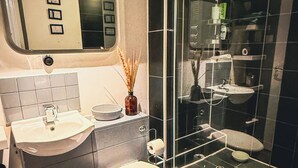 Et moderne badeværelse med en glasafskærmet brusekabine, vask og toilet.