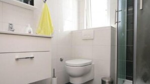 Un baño moderno con inodoro, lavabo y cabina de ducha.