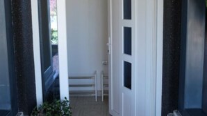 Un pasillo estrecho con una puerta blanca y un pequeño banco.