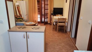 Un angolo cottura funzionale con frigorifero, un tavolo da pranzo con sedie e una televisione.