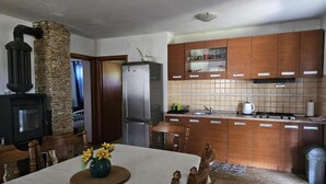 Una cocina con armarios de madera, estufa integrada y chimenea de piedra.