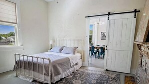 A bedroom with a bed, a ceiling fan, a window, and a door leading to another room. - Beautiful upstairs apartment for rent monthly near Audubon park (New Orleans)