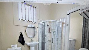 A bathroom with a toilet, sink, and glass-enclosed shower. - Beautiful upstairs apartment for rent monthly near Audubon park (New Orleans)