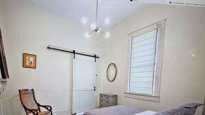 A bedroom with a bed, a chair, a window, and a door. - Beautiful upstairs apartment for rent monthly near Audubon park (New Orleans)