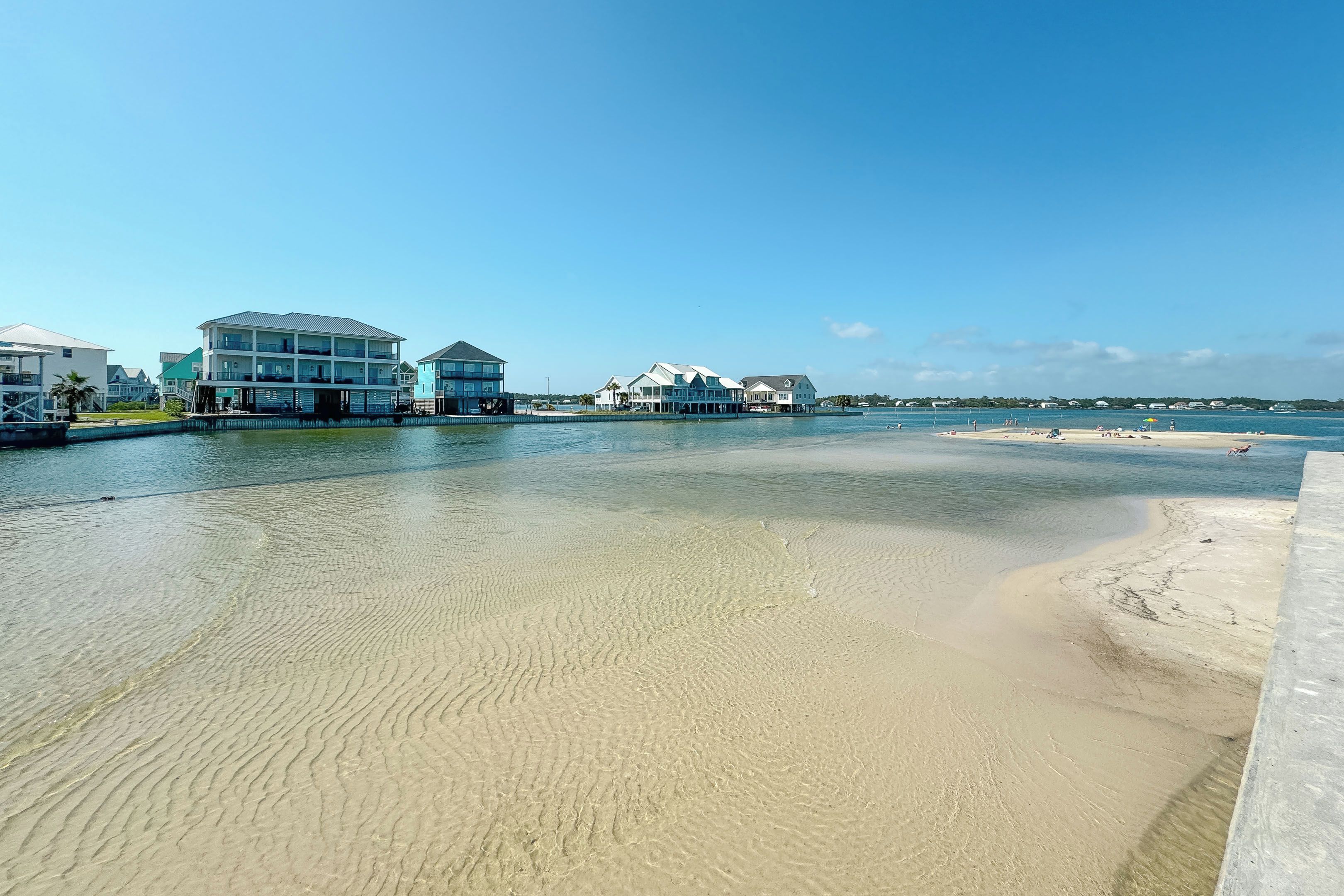 A beachfront property with multiple buildings, a sandy beach, and a calm water body.