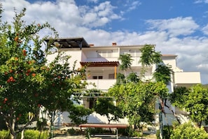 A two-story house with a balcony, surrounded by greenery and a clear sky. - Apartments Verović Rab Banjol - Two Bedroom Apartment With Terrace (A3) (Banjol)