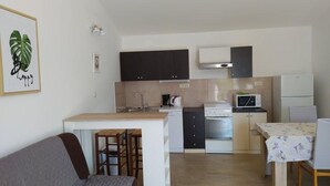A compact living space with a kitchenette, a dining area, and a sofa. - Apartments Verović Rab Banjol - One Bedroom Apartment With Terrace (A4) (Banjol)