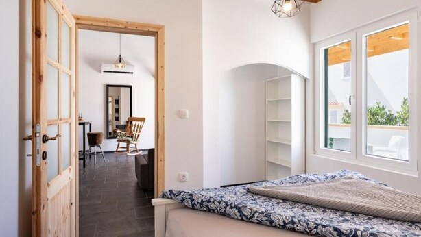 Una camera da letto con un letto, una porta in legno, una finestra e vista sull'esterno.