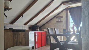 Une cuisine avec des poutres en bois, un réfrigérateur rouge et un coin repas comprenant une table et des chaises.
