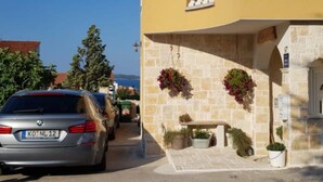 Un bâtiment jaune à la façade en pierre, doté d’un balcon et de jardinières suspendues.