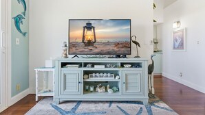 Olohuoneessa on vaaleansininen tv-taso, pieni sivupöytä ja koriste-esineitä.