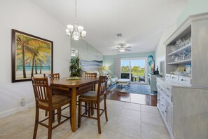 Un'area pranzo con un tavolo e sedie in legno, un lampadario e un dipinto raffigurante una spiaggia.