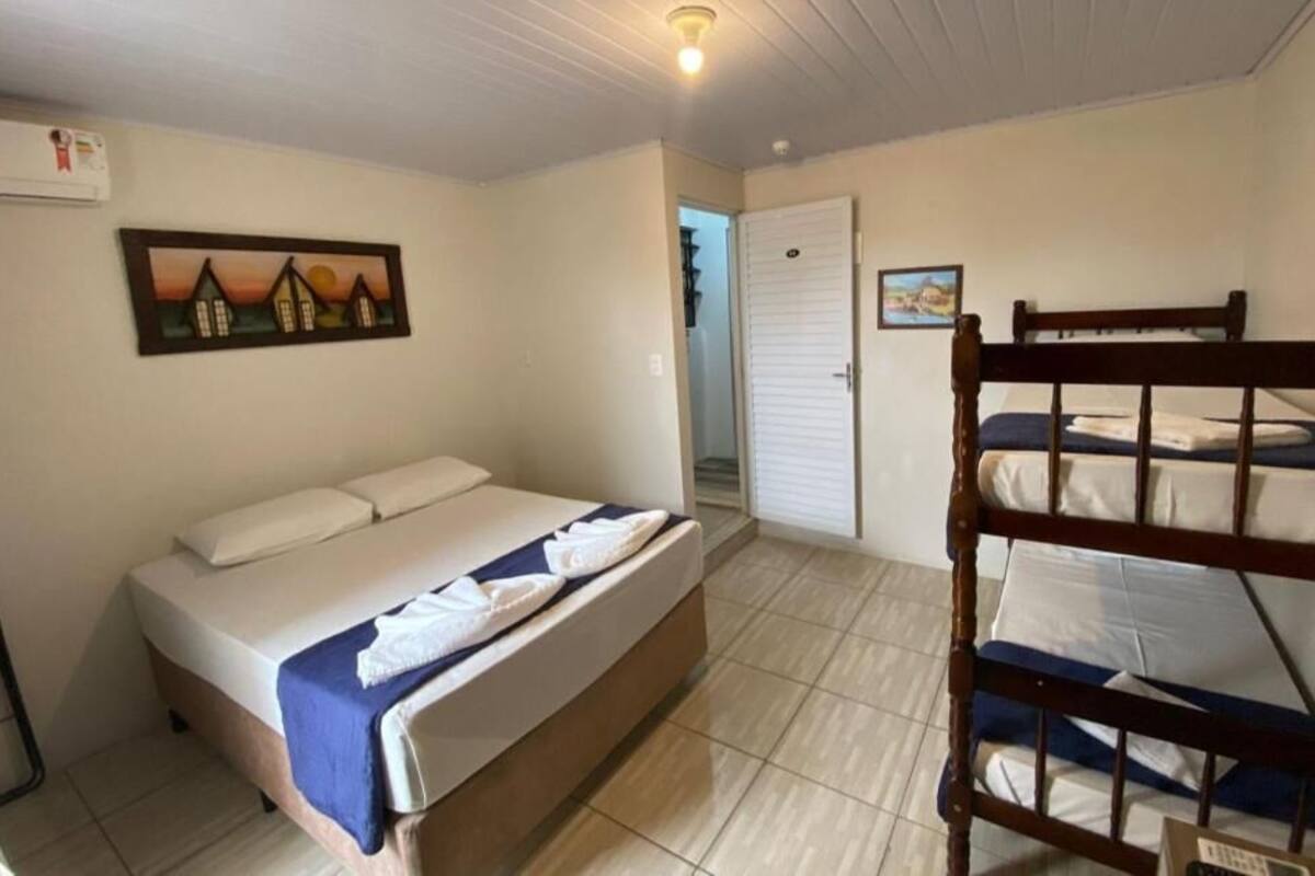 Ein Schlafzimmer mit einem Einzelbett, einem Etagenbett, einer Tür und einer Wand-Klimaanlage.