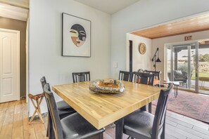 A dining area with a wooden table, black chairs, and a decorative bowl. There is a framed artwork on the wall and an exit sign. - Mountain-View Escape Near Santa Ana Casino! (Rio Rancho)