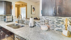 Cozinha moderna com bancadas de granito, eletrodomésticos de aço inoxidável e painel de azulejos.
