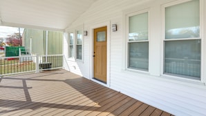 A covered porch with a wooden deck, white siding, and a front door with a window above it. - Walk to River, Parks & Dining: Family Home w/ Yard (National Park)