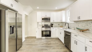 A modern kitchen with white cabinets, stainless steel appliances, and a tiled backsplash. - Walk to River, Parks & Dining: Family Home w/ Yard (National Park)