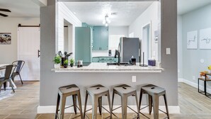 Une cuisine moderne dotée d’un îlot central, de tabourets de bar et donnant sur la salle à manger.