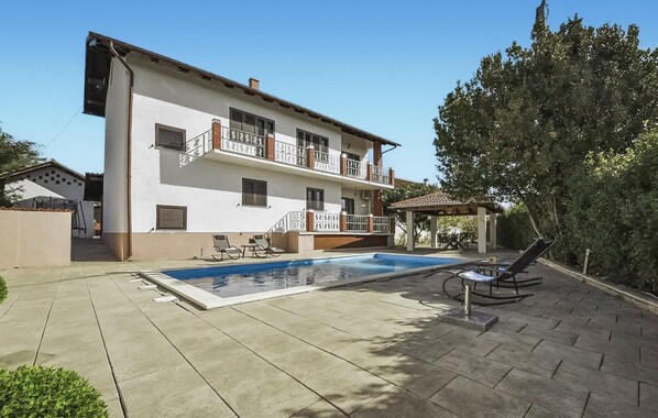 Un bâtiment à deux étages doté d’une piscine, d’un espace extérieur aménagé et d’une pergola.