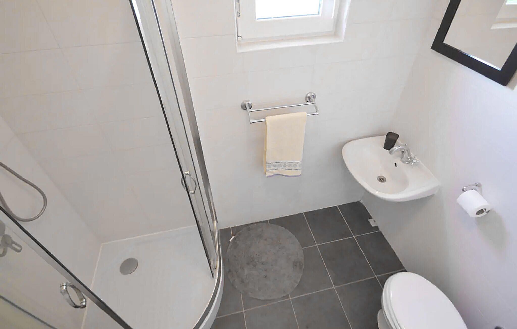 A small bathroom with a shower, a sink, and a toilet.